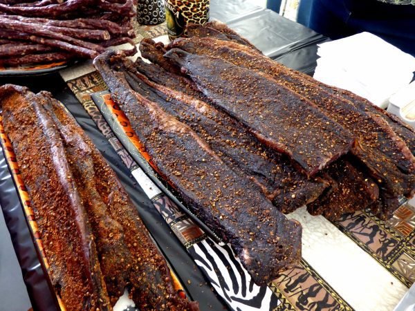 Traditional South African biltong beef strips seasoned with spices displayed on a patterned tablecloth.