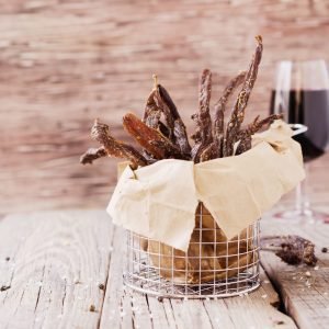 Chili Bites in a wire basket wrapped in parchment paper, with a glass of wine in the background.