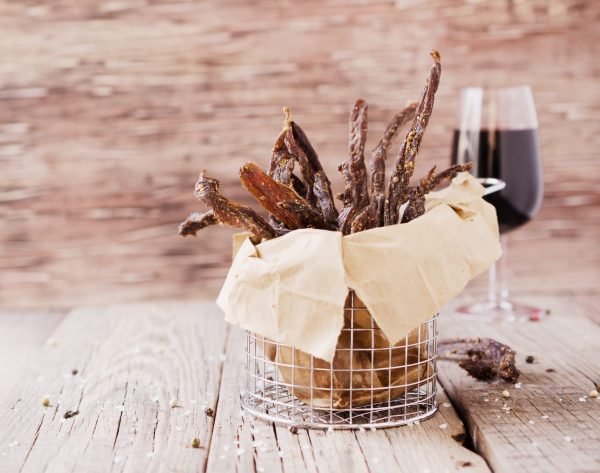 Chili Bites in a wire basket wrapped in parchment paper, with a glass of wine in the background.