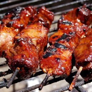 Four delicious, marinated, and grilled South African beef sosaties on skewers, served on a bbq grill.