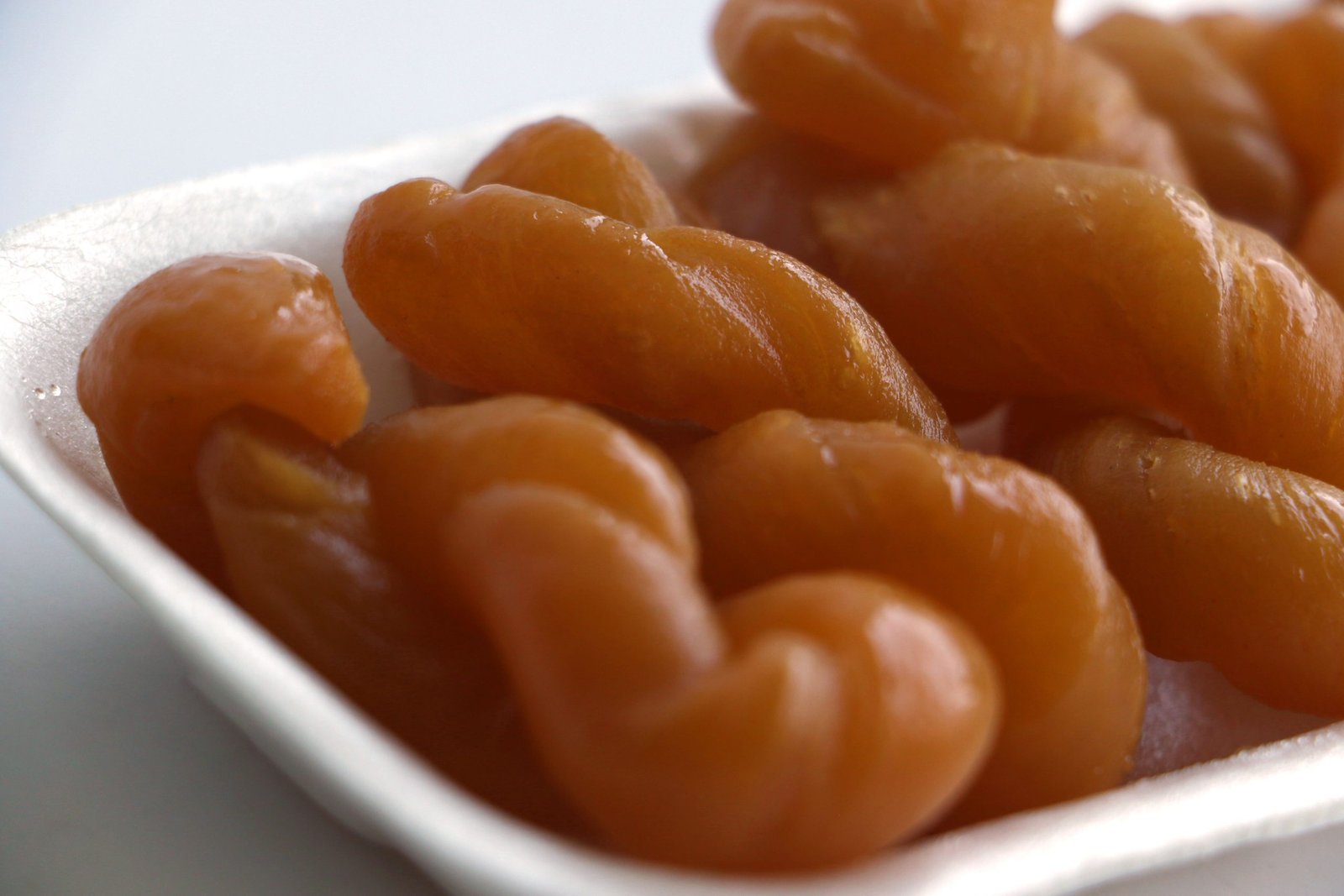 Golden-brown South African koeksisters coated in sweet syrup, showcasing their crispy, twisted texture. A traditional dessert loved for its rich flavor.