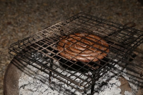 Durban hot lamb sausage coiled and grilling over hot coals on a braai