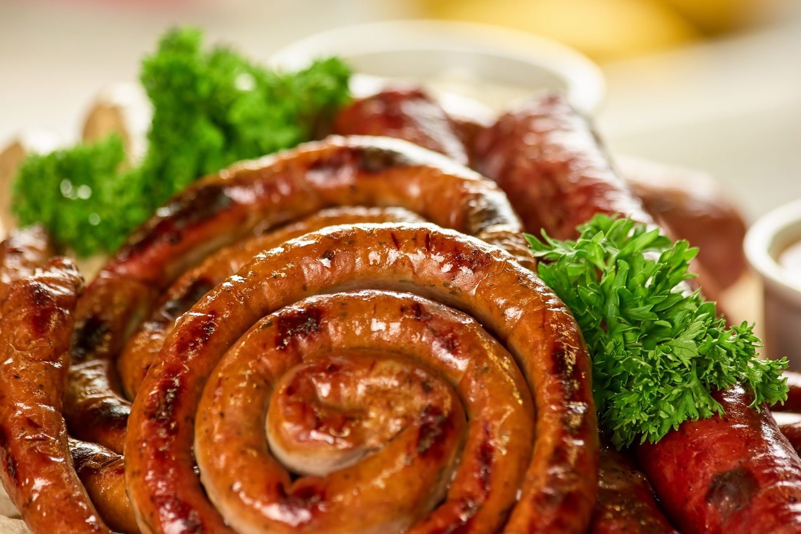 Grilled Hot Masala Lamb Sausage coiled on a platter with herbs, spicy South African Indian-style sausage
