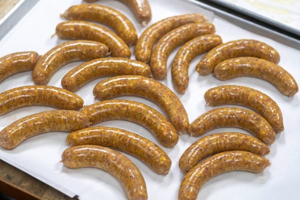 Freshly made Masala Lamb Sausages laid out on parchment paper, showcasing their rich colour and artisanal texture – South African-style spiced lamb sausage.