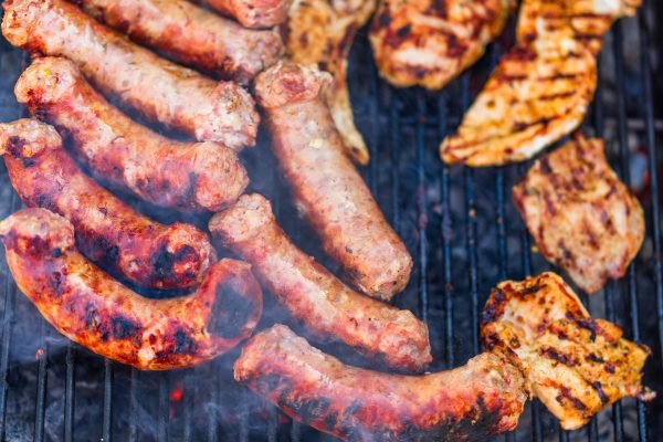 Juicy skaapwors lamb sausages and marinated chicken pieces sizzling on a South African-style braai.