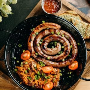 South African-style grilled skaapwors lamb sausage served in a spiral with chakalaka, cherry tomatoes, toast, and chutney