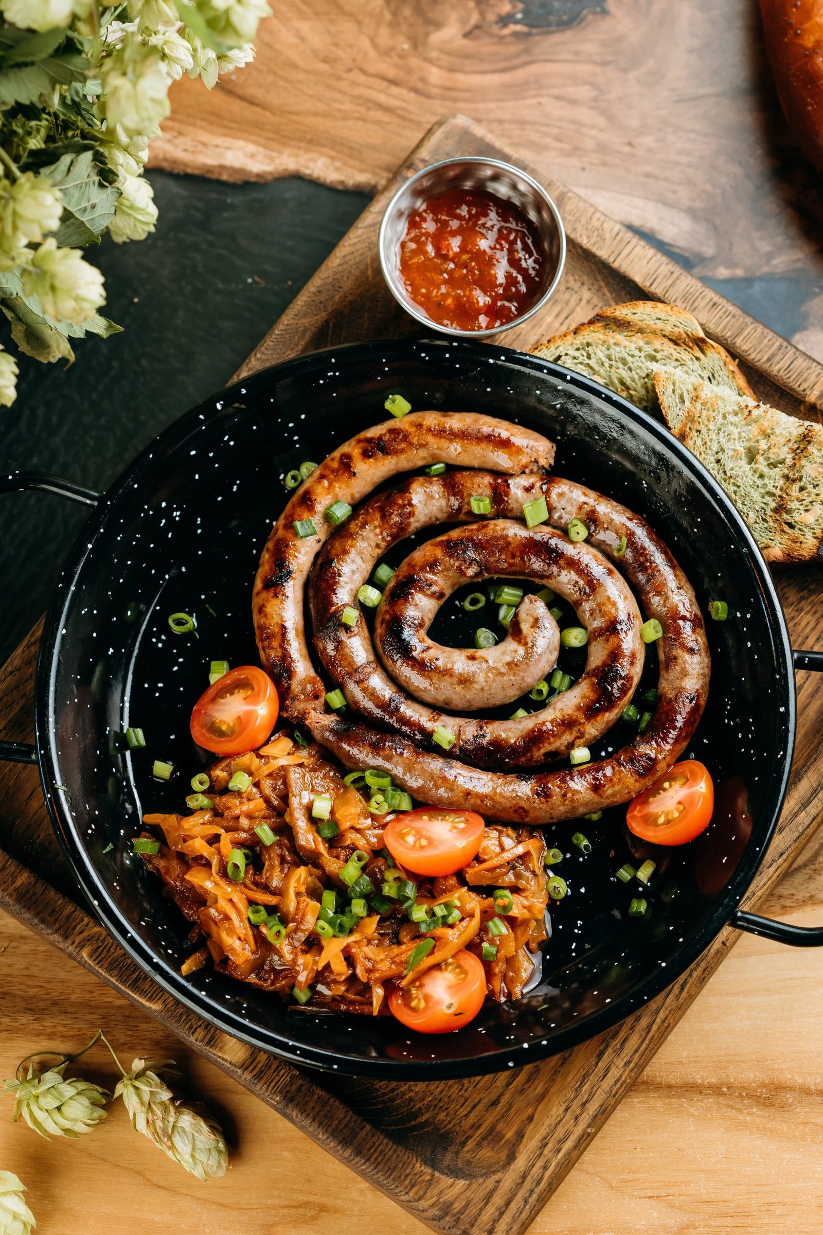 South African-style grilled skaapwors lamb sausage served in a spiral with chakalaka, cherry tomatoes, toast, and chutney