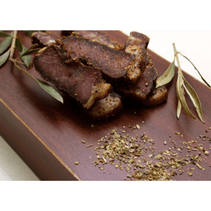 Bobaas premium sliced biltong pieces on wooden cutting board with coriander seeds and eucalyptus leaves, authentic South African air-dried beef snack