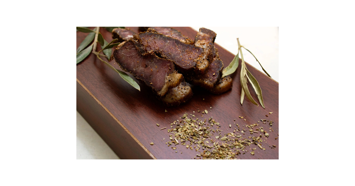 Bobaas premium sliced biltong pieces on wooden cutting board with coriander seeds and eucalyptus leaves, authentic South African air-dried beef snack